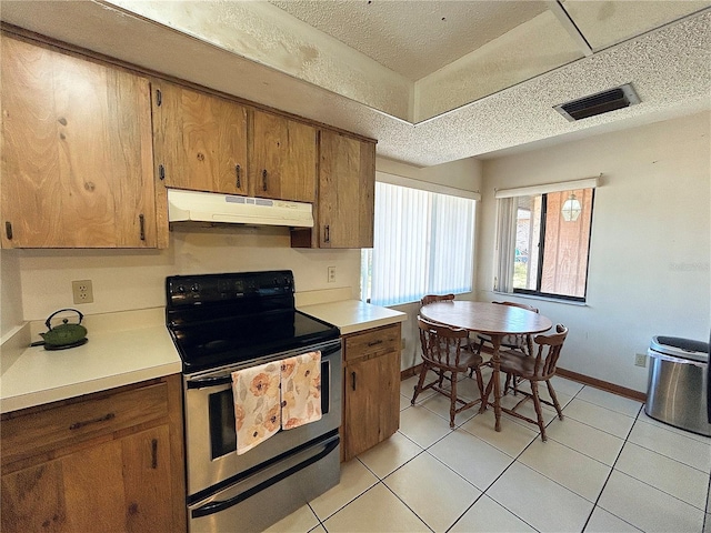 kitchen featuring light tile patterned floors, a textured ceiling, and electric stove