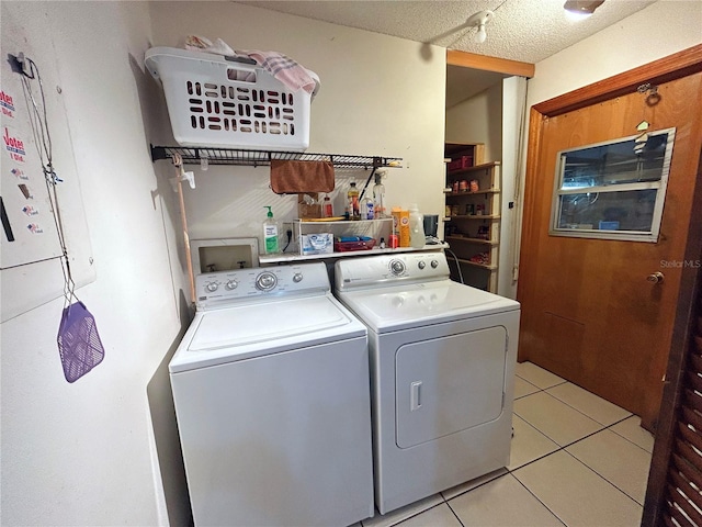 clothes washing area featuring light tile patterned floors, washer and dryer, and a textured ceiling