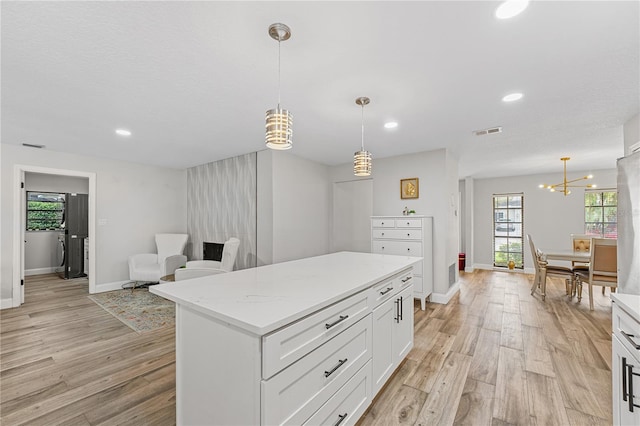 kitchen featuring white cabinets, light wood-type flooring, a center island, and decorative light fixtures