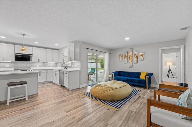 living room with sink, light hardwood / wood-style floors, and a textured ceiling