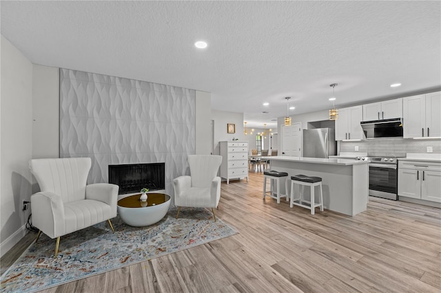 living room featuring a fireplace, a textured ceiling, and light wood-type flooring