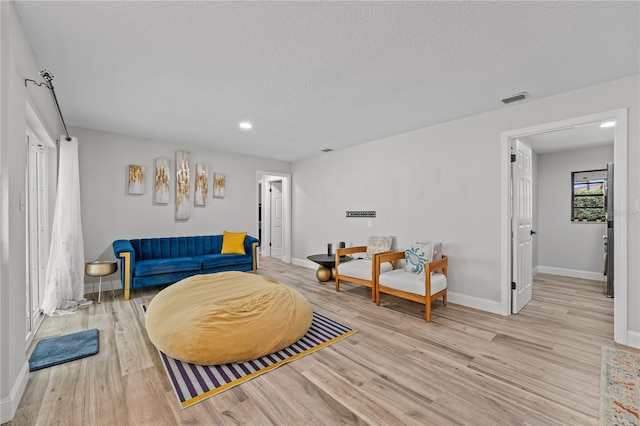 living room featuring a textured ceiling and light hardwood / wood-style floors