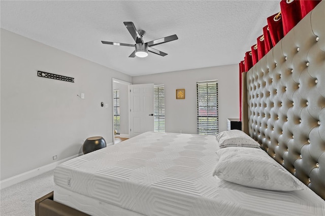 carpeted bedroom featuring ceiling fan and a textured ceiling