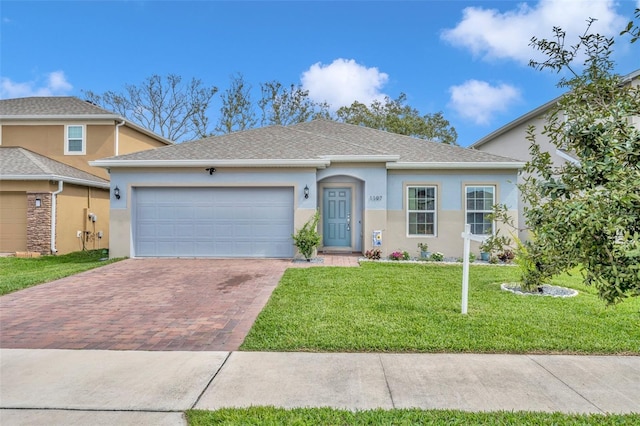 ranch-style home with a garage, decorative driveway, a front lawn, and stucco siding