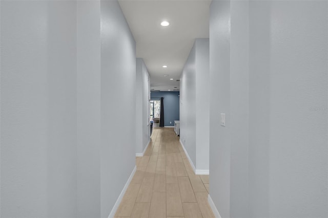 corridor featuring baseboards, recessed lighting, and light wood-style floors