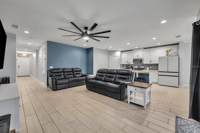 living area featuring light wood-type flooring, visible vents, and recessed lighting