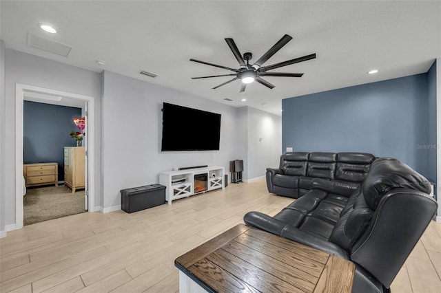 living room featuring light wood finished floors, visible vents, attic access, ceiling fan, and baseboards