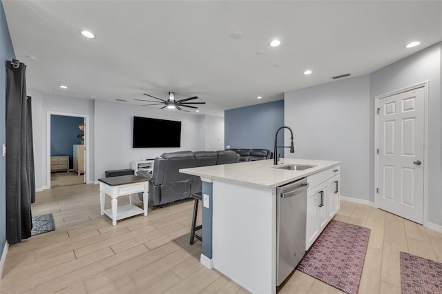 kitchen featuring white cabinets, dishwasher, open floor plan, light countertops, and a sink