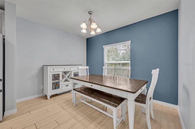 dining room with light wood-style floors, a notable chandelier, and baseboards