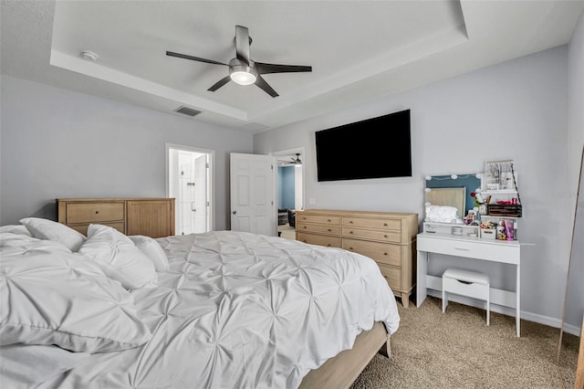 bedroom with light carpet, visible vents, baseboards, ceiling fan, and a tray ceiling