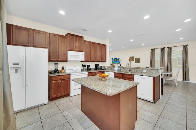 kitchen featuring sink, light tile patterned flooring, kitchen peninsula, white appliances, and a kitchen island