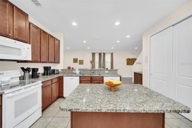 kitchen featuring white appliances, sink, light tile patterned floors, light stone counters, and kitchen peninsula