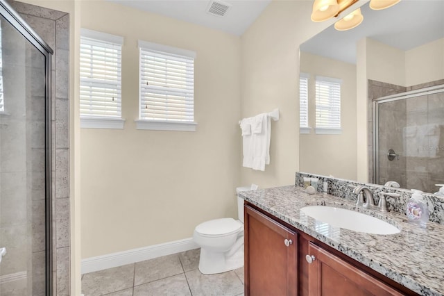 bathroom featuring toilet, vanity, tile patterned floors, and a shower with shower door