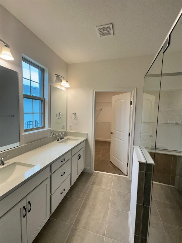 bathroom featuring vanity, tile patterned flooring, a textured ceiling, and a shower