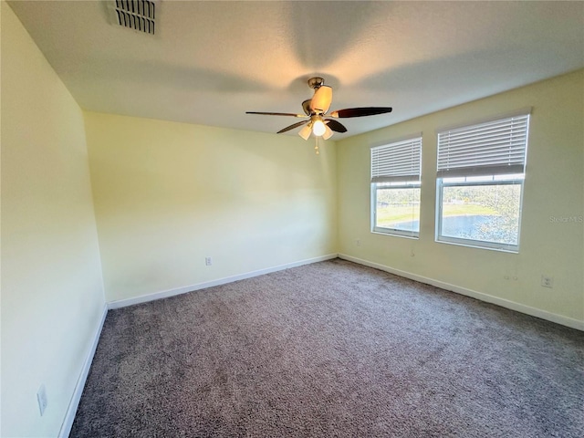 spare room with ceiling fan and dark colored carpet