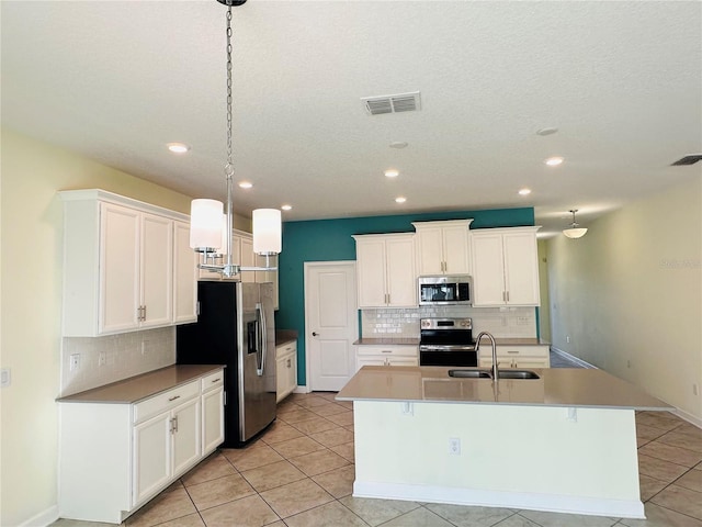 kitchen featuring sink, hanging light fixtures, an island with sink, light tile patterned floors, and appliances with stainless steel finishes