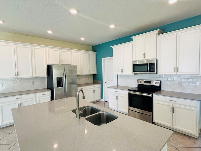 kitchen with white cabinets, a center island with sink, sink, and appliances with stainless steel finishes