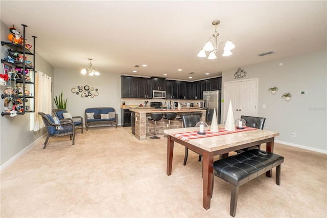 dining area featuring sink, light colored carpet, and an inviting chandelier