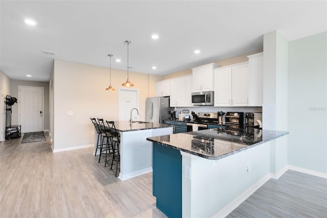 kitchen with a center island, hanging light fixtures, dark stone counters, a breakfast bar area, and appliances with stainless steel finishes