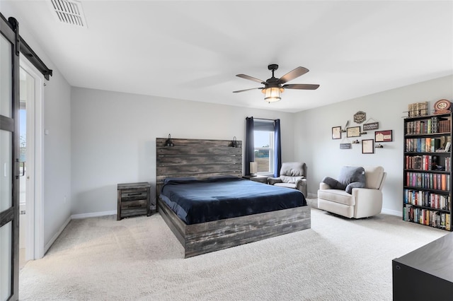 carpeted bedroom featuring ceiling fan and a barn door