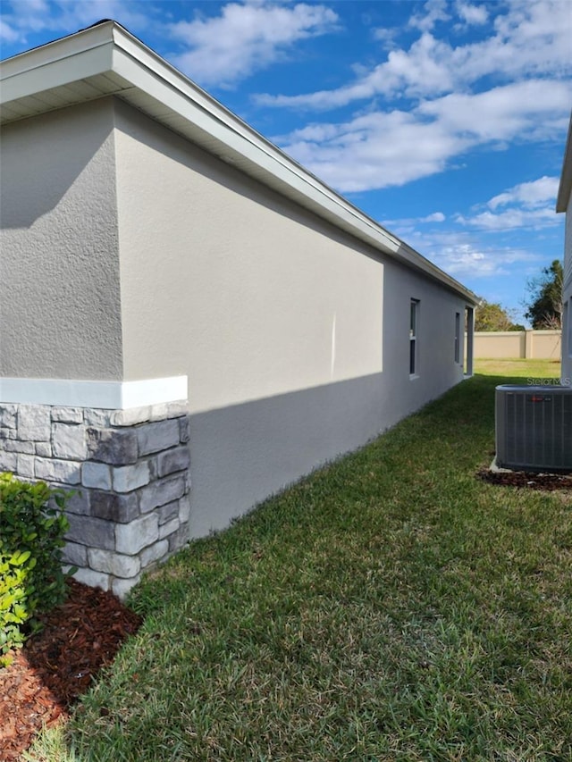 view of side of property featuring a lawn and cooling unit