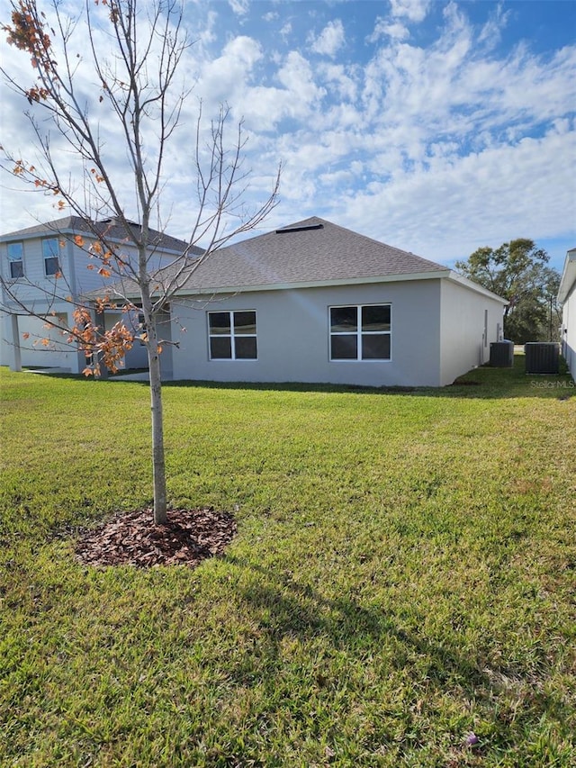 rear view of property with a yard and central AC unit