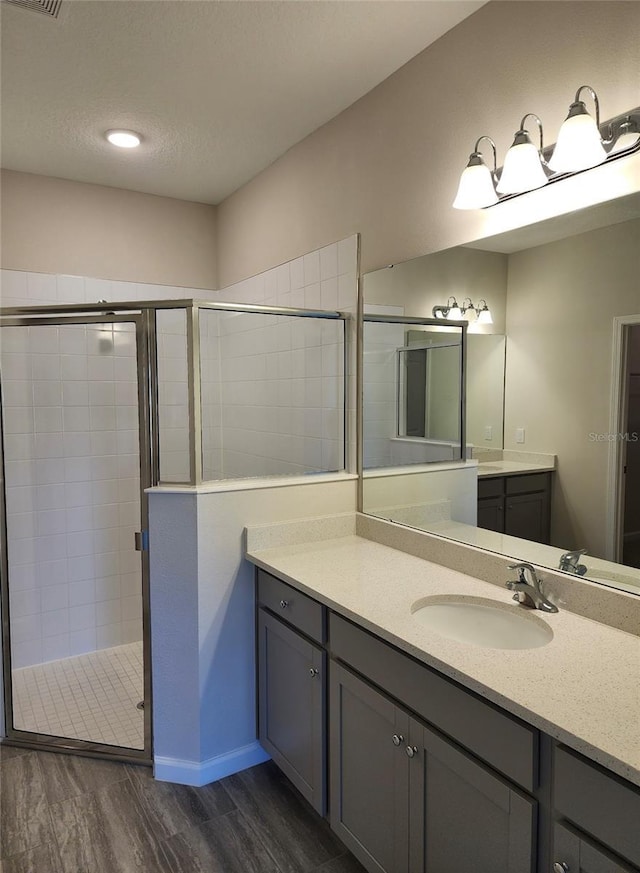 bathroom with hardwood / wood-style floors, vanity, and a shower with door