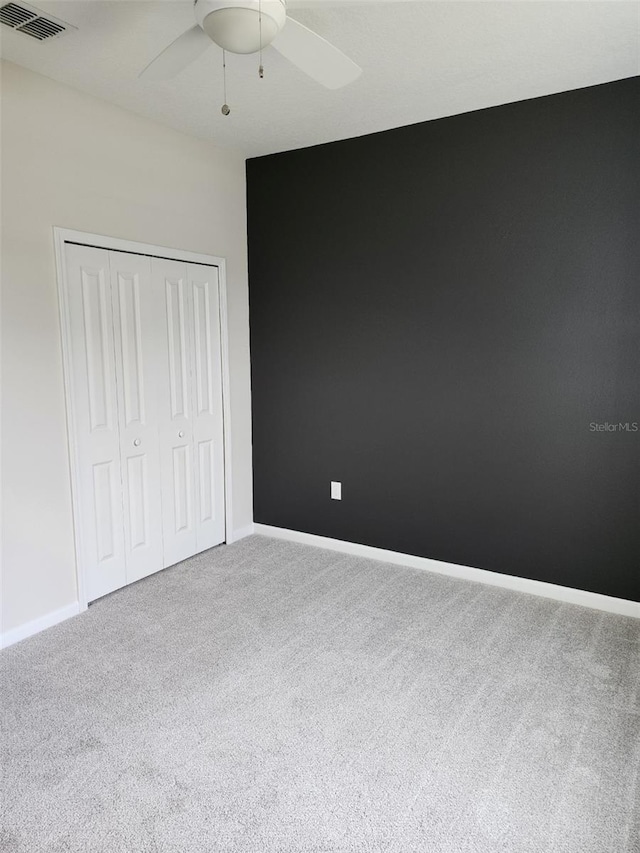 unfurnished bedroom featuring carpet flooring, ceiling fan, and a closet