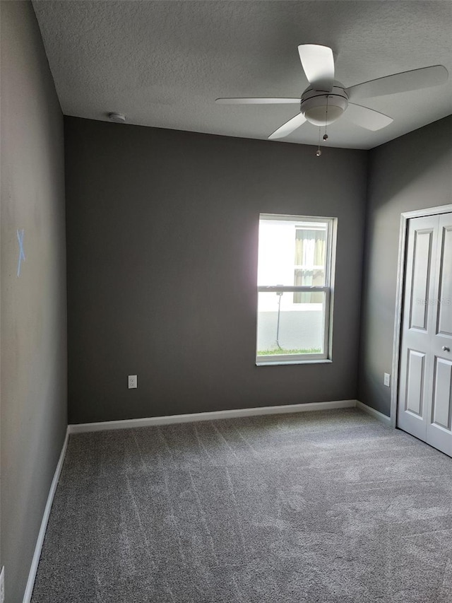 carpeted spare room with ceiling fan and a textured ceiling