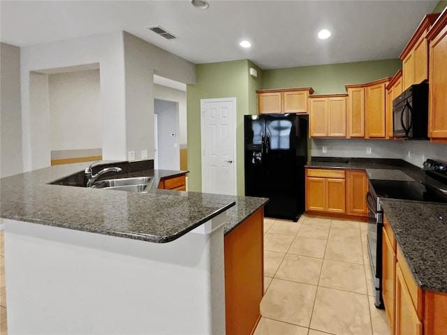 kitchen with dark stone counters, black appliances, sink, light tile patterned floors, and kitchen peninsula