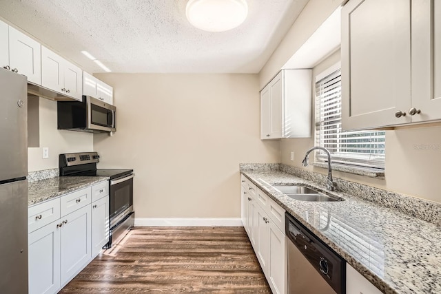 kitchen with sink, light stone countertops, white cabinets, and appliances with stainless steel finishes