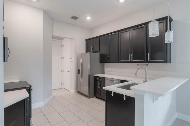 kitchen with kitchen peninsula, stainless steel fridge, a kitchen breakfast bar, sink, and hanging light fixtures