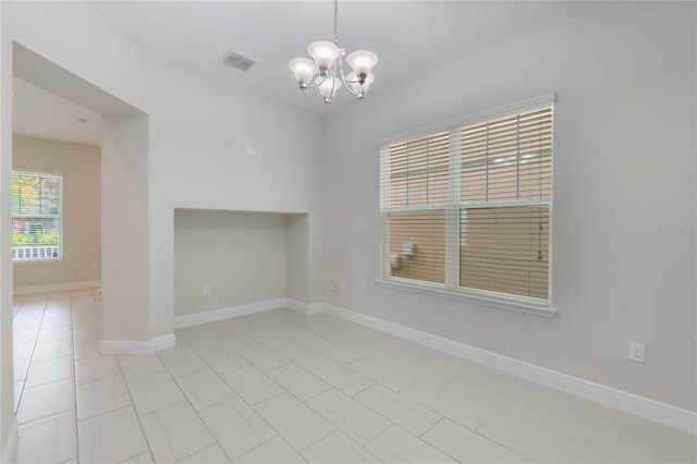 spare room featuring light tile patterned floors and a chandelier