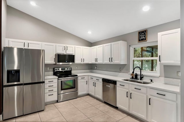 kitchen with appliances with stainless steel finishes, vaulted ceiling, sink, light tile patterned floors, and white cabinets