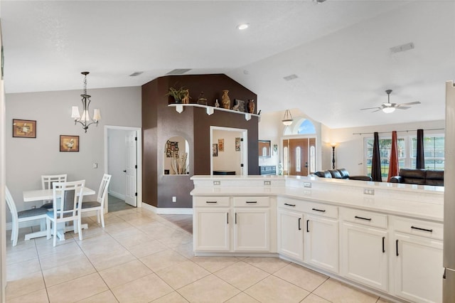 kitchen with ceiling fan with notable chandelier, hanging light fixtures, vaulted ceiling, light tile patterned floors, and white cabinetry