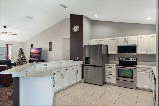 kitchen with kitchen peninsula, vaulted ceiling, stainless steel appliances, and white cabinetry