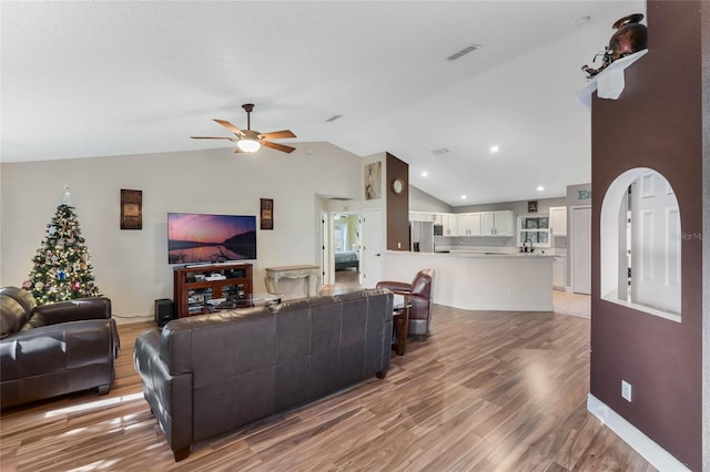 living room featuring hardwood / wood-style floors, ceiling fan, and vaulted ceiling