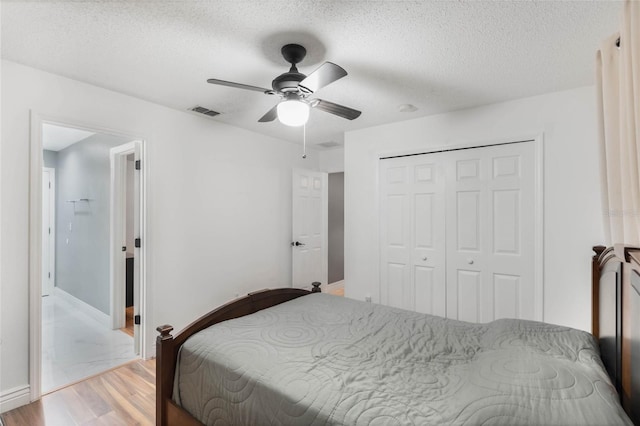 bedroom with a textured ceiling, light wood-type flooring, a closet, and ceiling fan