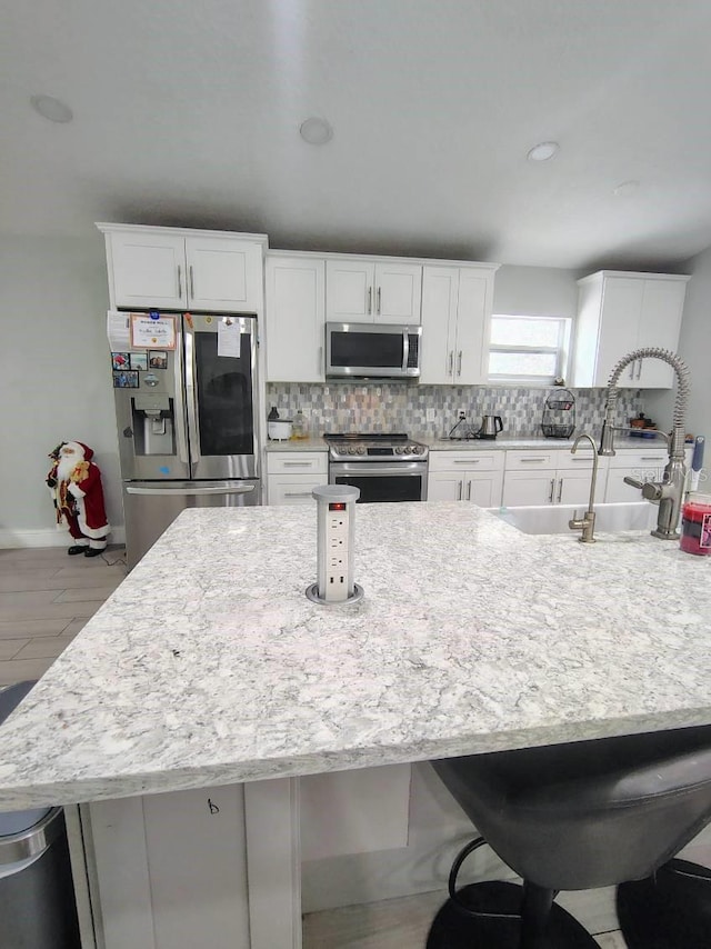 kitchen with a breakfast bar area, white cabinetry, sink, and stainless steel appliances