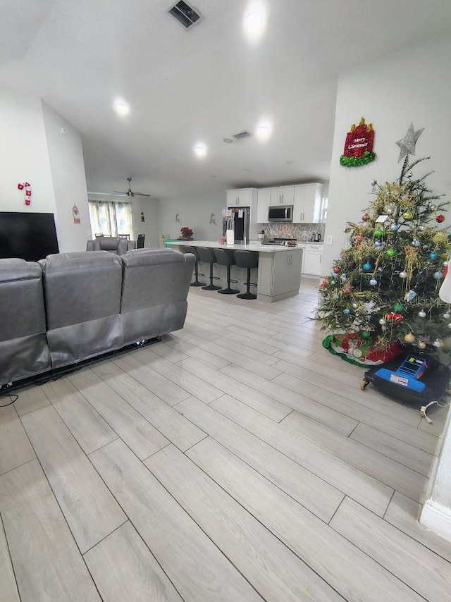 living room with ceiling fan and light wood-type flooring