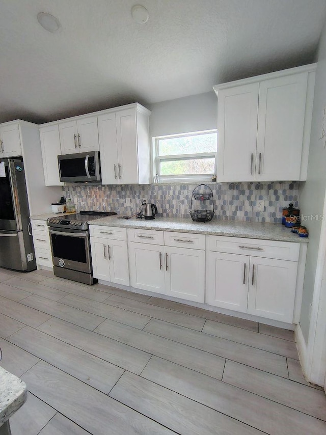 kitchen with white cabinets, appliances with stainless steel finishes, and backsplash