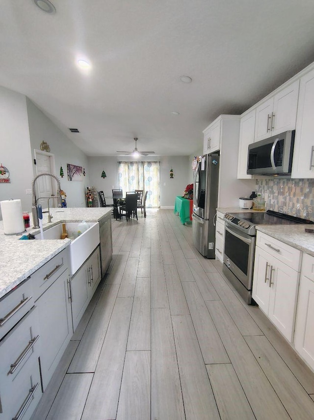 kitchen featuring stainless steel appliances, white cabinetry, ceiling fan, and sink