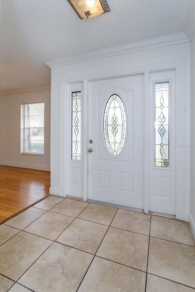 tiled foyer with a wealth of natural light, crown molding, and a textured ceiling