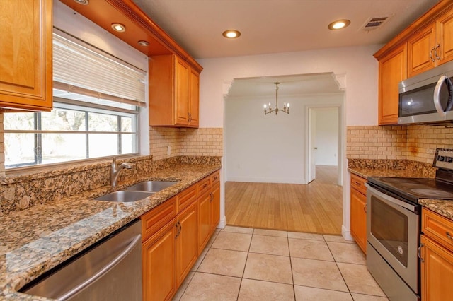 kitchen with hanging light fixtures, sink, light tile patterned floors, appliances with stainless steel finishes, and a chandelier