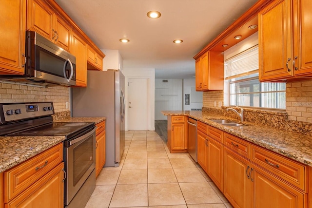 kitchen featuring decorative backsplash, appliances with stainless steel finishes, light stone counters, sink, and light tile patterned floors