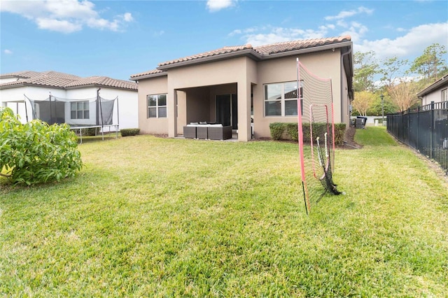 rear view of property with a lawn, outdoor lounge area, and a trampoline