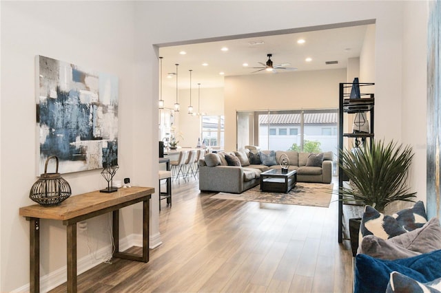 living room featuring ceiling fan, wood-type flooring, and a high ceiling