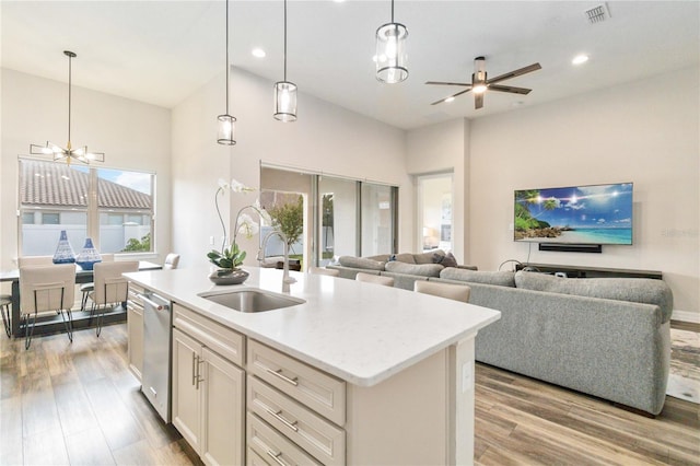 kitchen featuring sink, light hardwood / wood-style floors, decorative light fixtures, a kitchen island with sink, and ceiling fan with notable chandelier