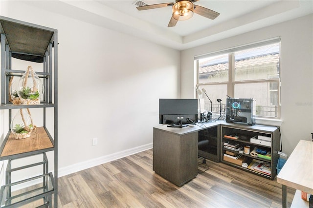 office space with hardwood / wood-style flooring, a raised ceiling, and ceiling fan