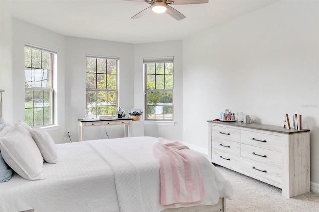 bedroom with ceiling fan, light carpet, and multiple windows